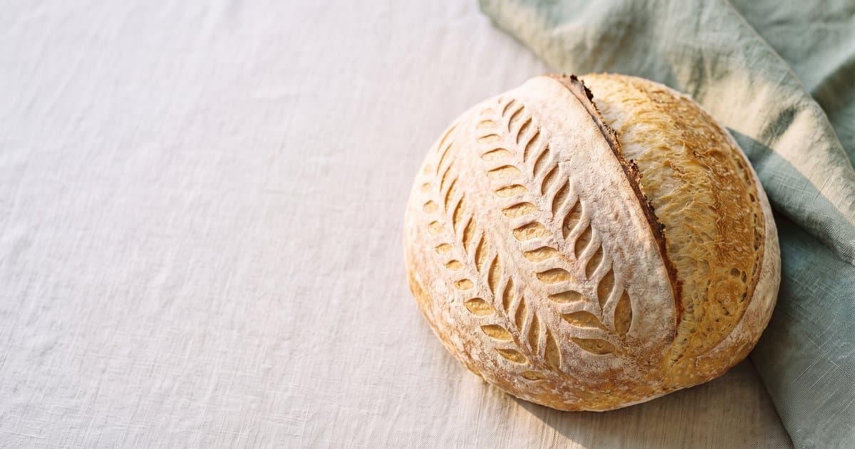 A scored sourdough loaf on a linen cloth